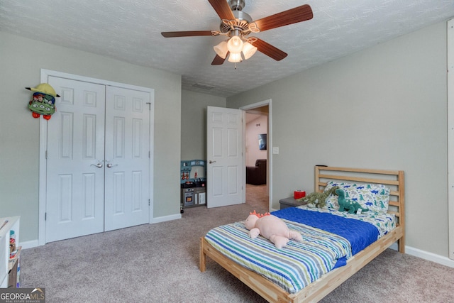 carpeted bedroom with a textured ceiling, ceiling fan, and a closet