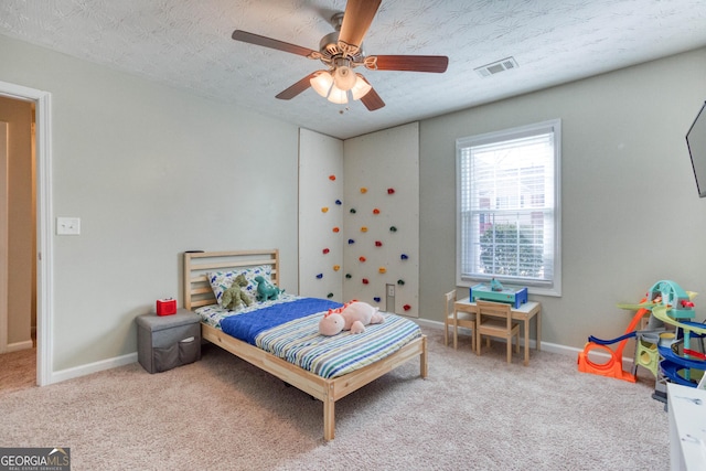 bedroom with carpet, a textured ceiling, and ceiling fan