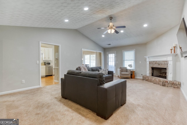 living room featuring vaulted ceiling, light carpet, a textured ceiling, ceiling fan, and a fireplace