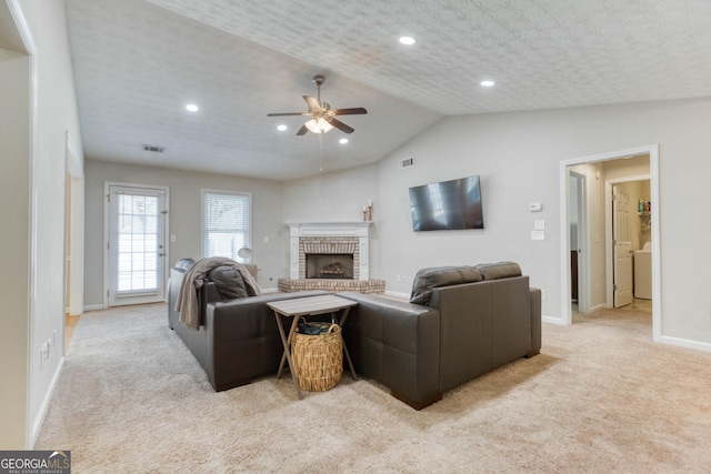 carpeted living room featuring lofted ceiling, a textured ceiling, a fireplace, and ceiling fan