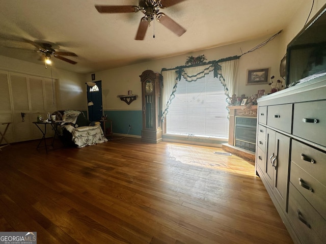 unfurnished room featuring ceiling fan, a tiled fireplace, hardwood / wood-style floors, and a textured ceiling