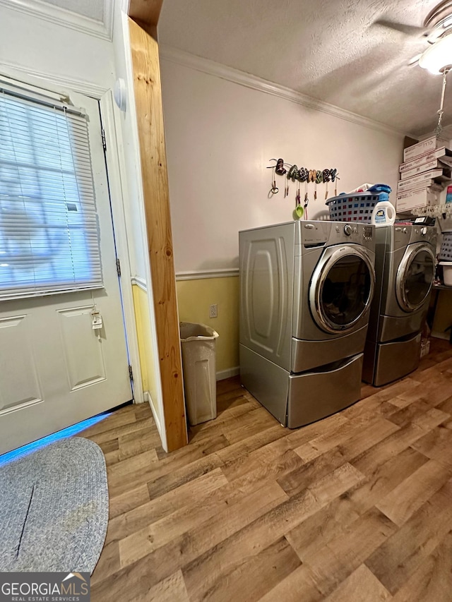 laundry room with separate washer and dryer, crown molding, a textured ceiling, and light wood-type flooring