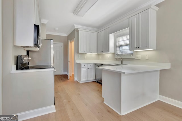 kitchen featuring appliances with stainless steel finishes, sink, white cabinets, light hardwood / wood-style floors, and kitchen peninsula