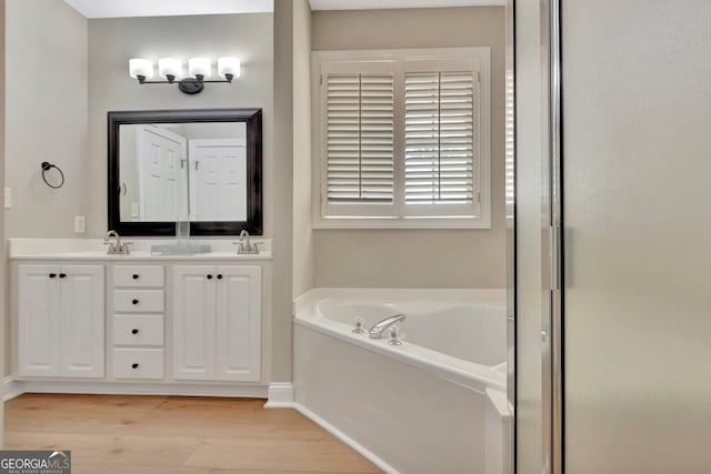 bathroom with wood-type flooring, vanity, and a tub