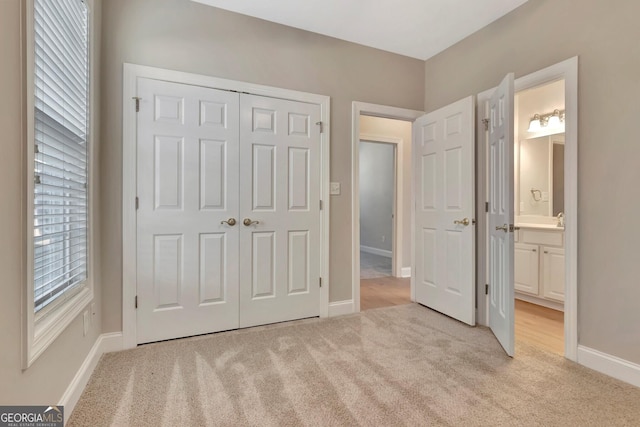 unfurnished bedroom featuring connected bathroom, light carpet, and a closet