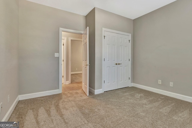 unfurnished bedroom with light colored carpet and a closet