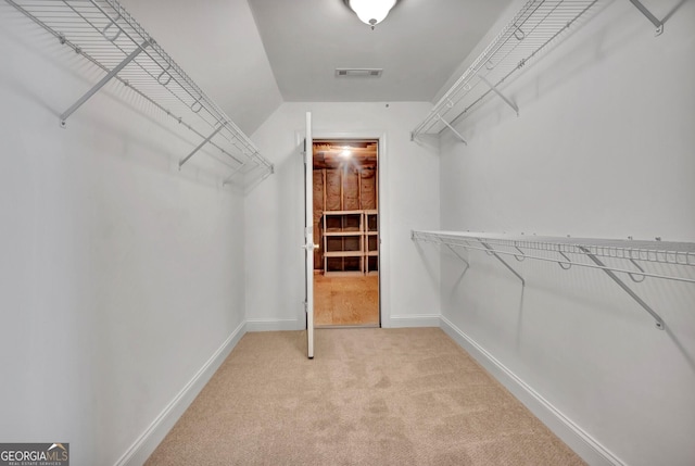 walk in closet featuring light colored carpet