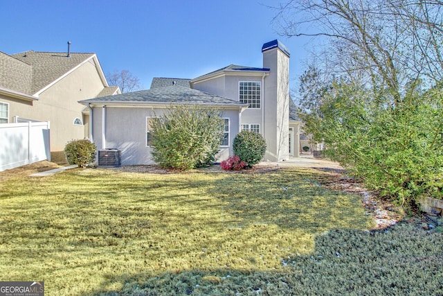 back of property featuring central AC unit and a lawn