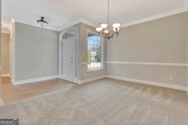 carpeted empty room featuring crown molding and a notable chandelier