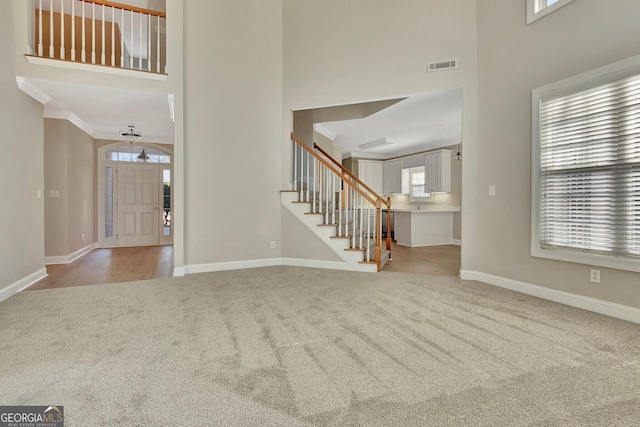 foyer featuring a towering ceiling, plenty of natural light, and light colored carpet