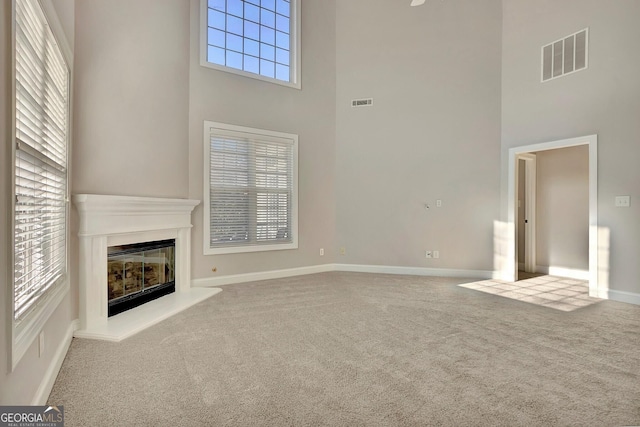 unfurnished living room featuring a high ceiling, carpet, and a wealth of natural light