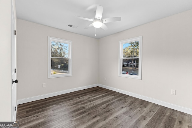 spare room featuring ceiling fan, a healthy amount of sunlight, and dark hardwood / wood-style floors