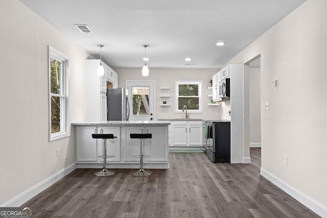 kitchen featuring sink, white cabinetry, stainless steel appliances, a kitchen breakfast bar, and decorative light fixtures