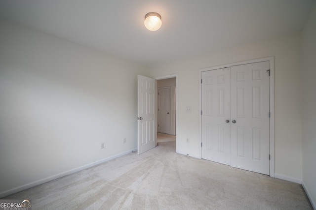 unfurnished bedroom featuring light carpet and a closet