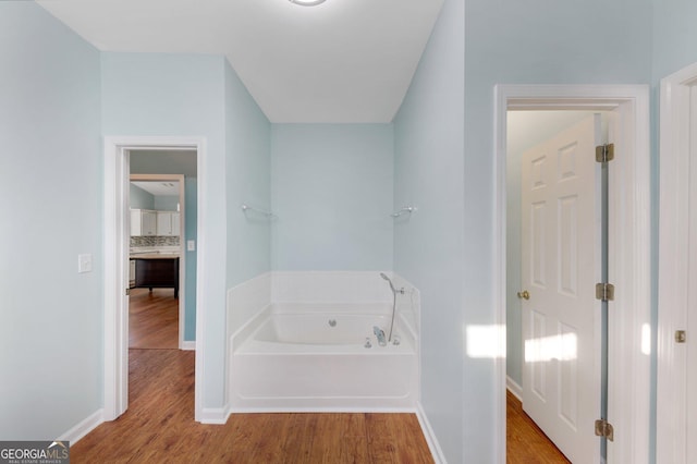 bathroom with a washtub, wood-type flooring, and tasteful backsplash