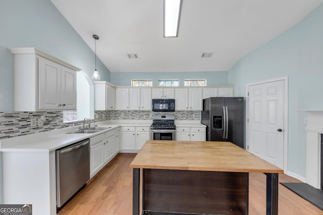 kitchen featuring appliances with stainless steel finishes, white cabinetry, sink, backsplash, and hanging light fixtures