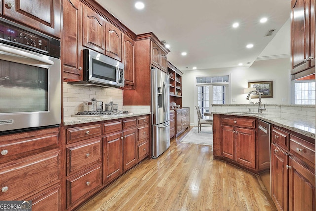 kitchen with light stone counters, decorative backsplash, light hardwood / wood-style flooring, and appliances with stainless steel finishes