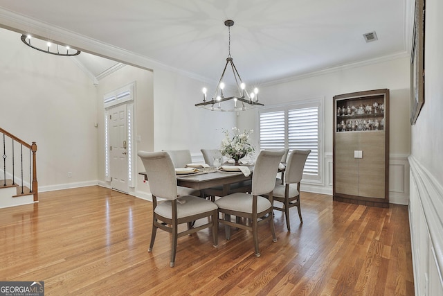 dining space with hardwood / wood-style flooring, crown molding, and a chandelier