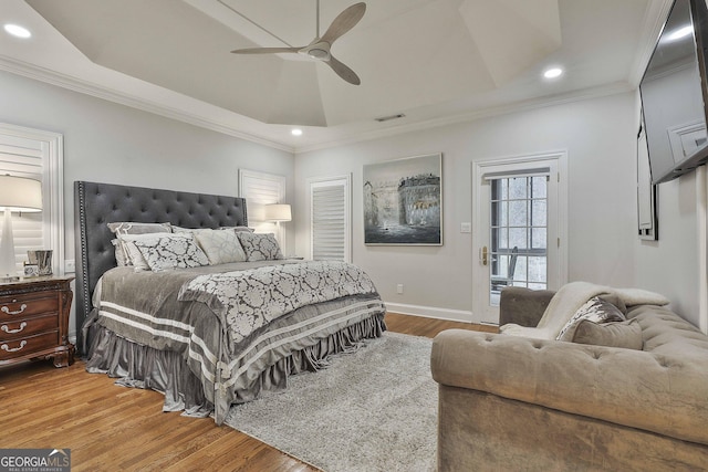 bedroom featuring hardwood / wood-style flooring, crown molding, ceiling fan, and a tray ceiling