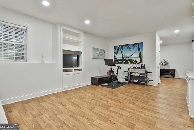 workout area with built in shelves and light wood-type flooring