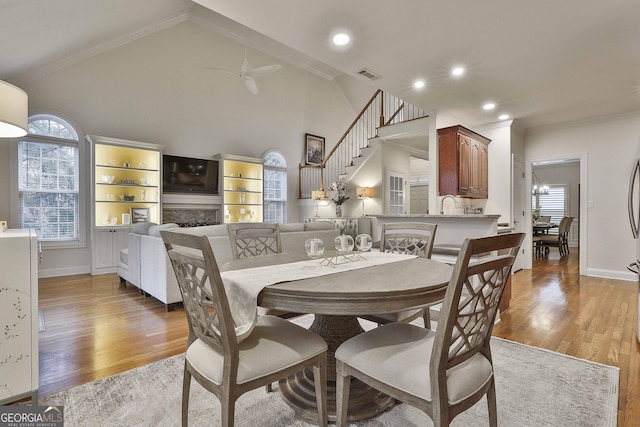 dining space with ceiling fan, high vaulted ceiling, sink, and light hardwood / wood-style floors