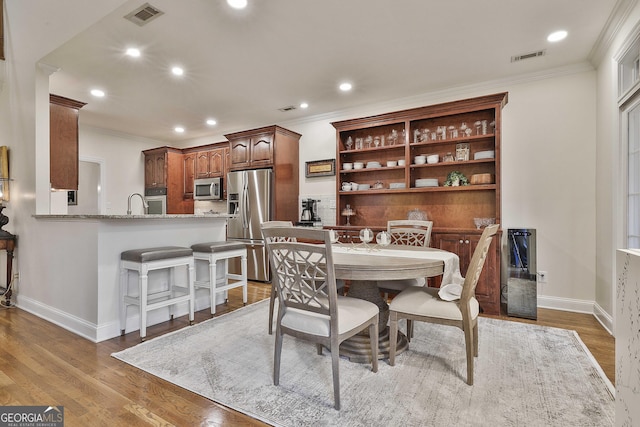 dining space featuring ornamental molding and light hardwood / wood-style floors