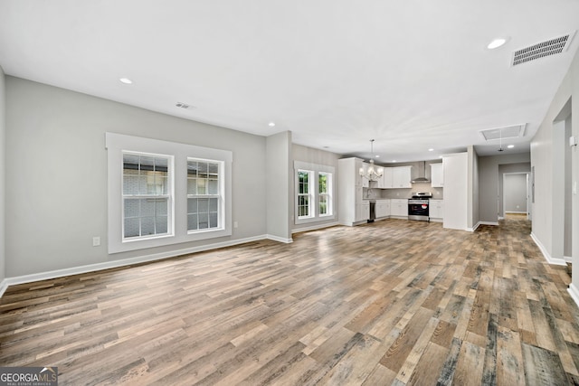 unfurnished living room with an inviting chandelier and wood-type flooring