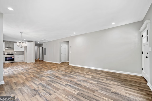 unfurnished living room featuring hardwood / wood-style flooring and a chandelier