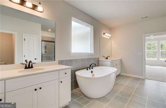 bathroom with independent shower and bath, vanity, tile walls, and tile patterned floors