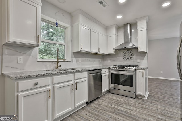 kitchen with white cabinetry, appliances with stainless steel finishes, and wall chimney range hood