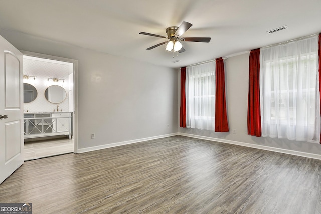 empty room featuring ceiling fan, wood-type flooring, and a wealth of natural light