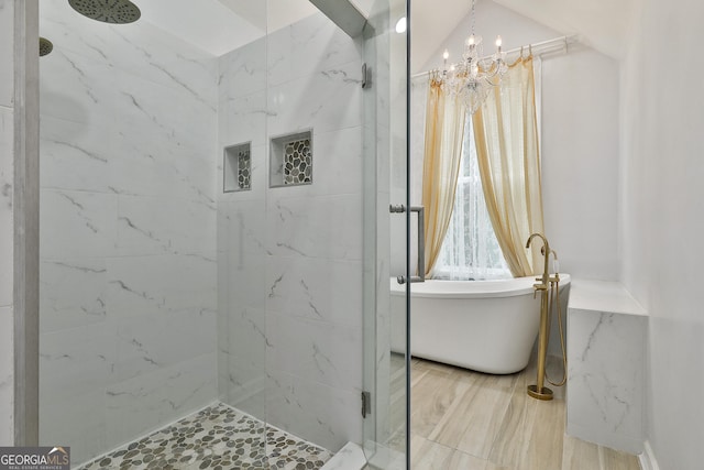 bathroom featuring a notable chandelier, hardwood / wood-style flooring, and tiled shower