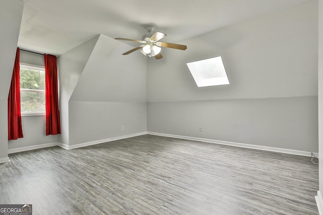 bonus room with lofted ceiling with skylight, wood-type flooring, and ceiling fan