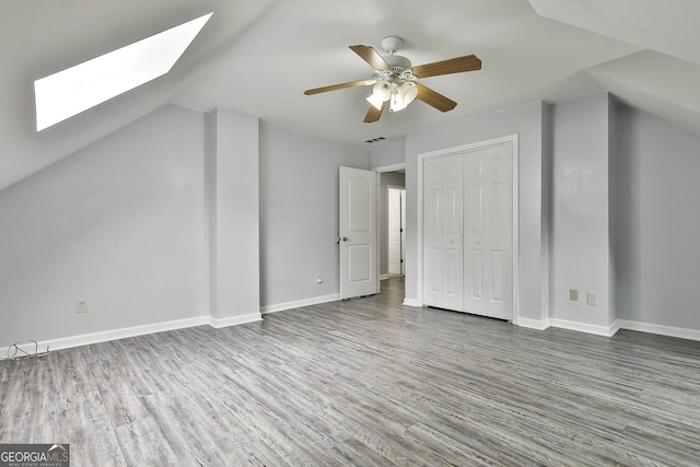 additional living space with hardwood / wood-style flooring, lofted ceiling with skylight, and ceiling fan