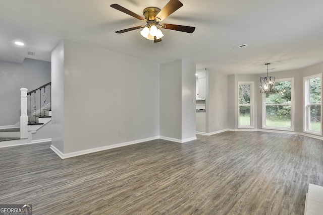 unfurnished living room with ceiling fan with notable chandelier and dark hardwood / wood-style floors