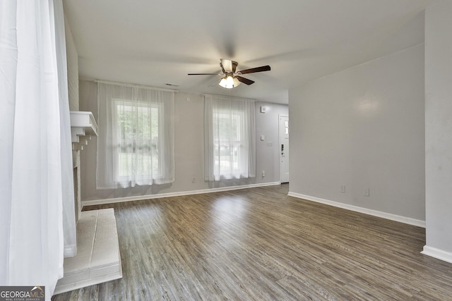 unfurnished room with a brick fireplace, dark hardwood / wood-style floors, and ceiling fan