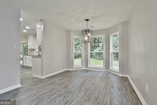 unfurnished dining area featuring an inviting chandelier, hardwood / wood-style floors, and sink