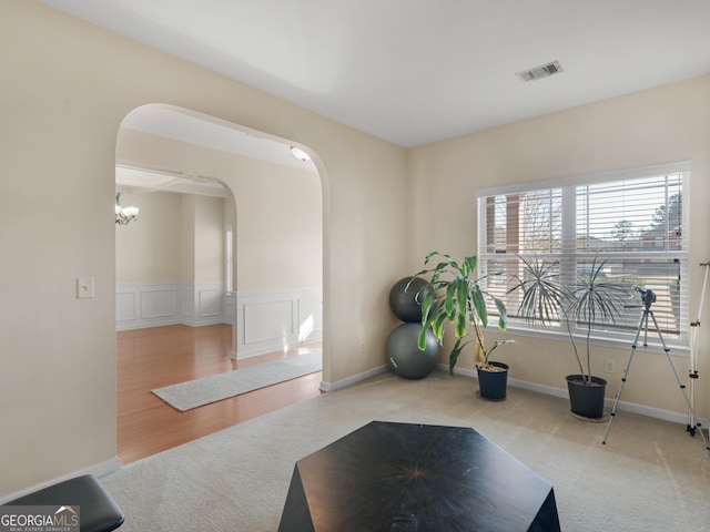 exercise room with light colored carpet and a chandelier