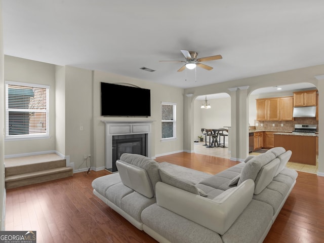 living room with ceiling fan with notable chandelier and hardwood / wood-style floors