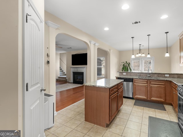 kitchen with sink, decorative light fixtures, a center island, stone counters, and stainless steel appliances