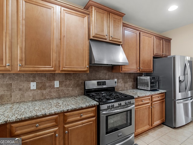 kitchen with tasteful backsplash, light tile patterned floors, light stone counters, and stainless steel appliances