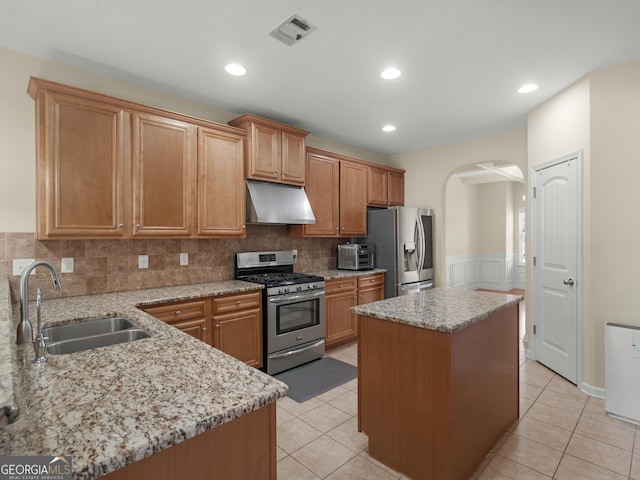 kitchen featuring light tile patterned flooring, sink, a center island, stainless steel appliances, and light stone countertops