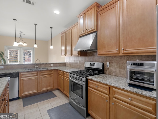 kitchen featuring sink, light stone counters, hanging light fixtures, appliances with stainless steel finishes, and decorative backsplash