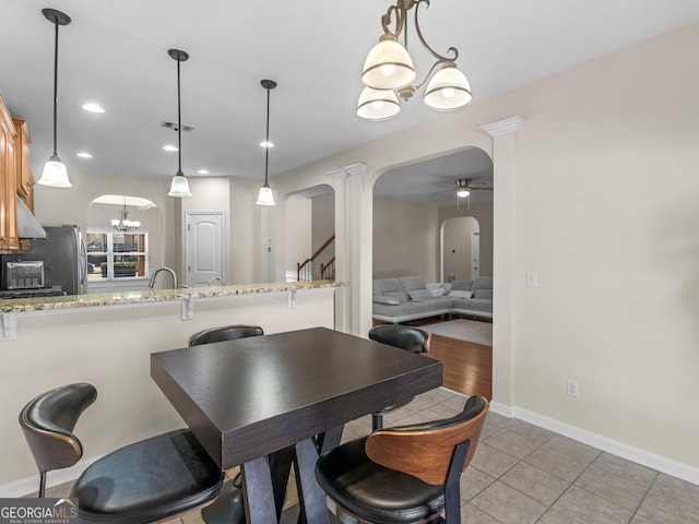 tiled dining room with ceiling fan with notable chandelier