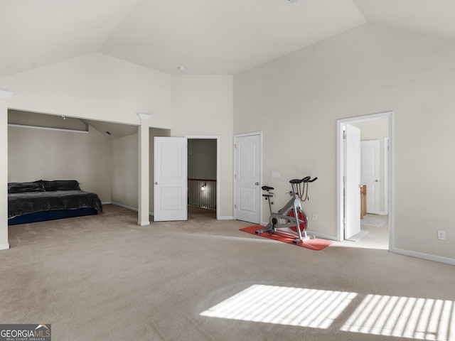 carpeted bedroom featuring high vaulted ceiling and ensuite bath