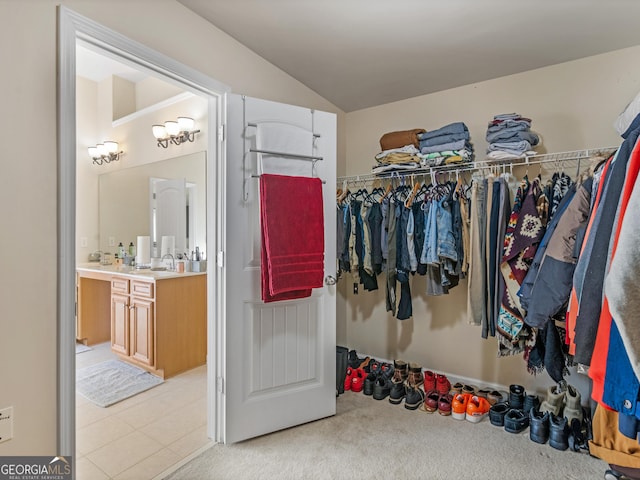 walk in closet with vaulted ceiling, light colored carpet, and sink