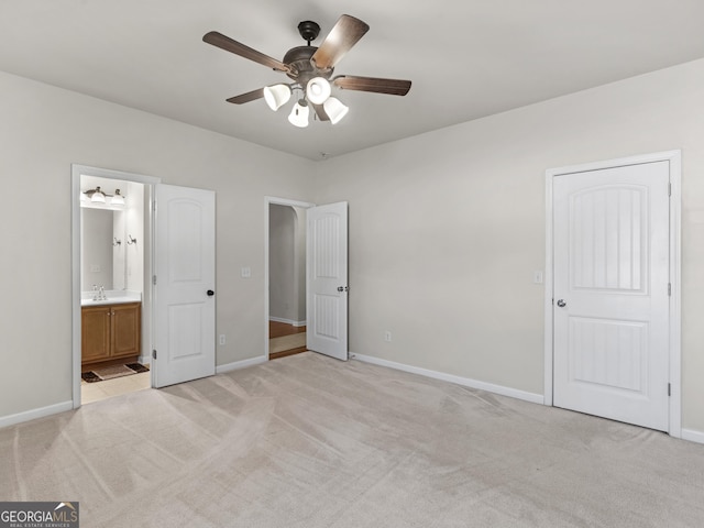 unfurnished bedroom with sink, light colored carpet, ceiling fan, and ensuite bathroom