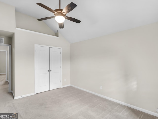 unfurnished bedroom featuring ceiling fan, high vaulted ceiling, a closet, and light carpet