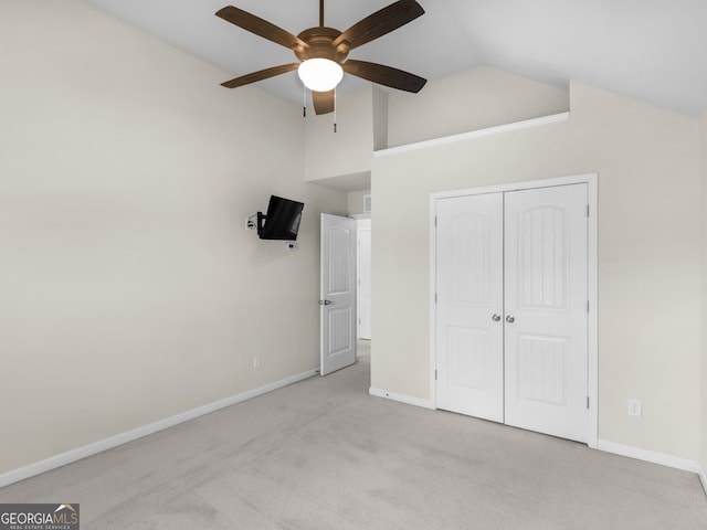 unfurnished bedroom featuring high vaulted ceiling, light carpet, ceiling fan, and a closet