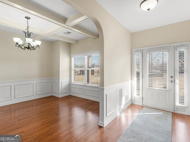 entryway with beamed ceiling, wood-type flooring, coffered ceiling, and an inviting chandelier